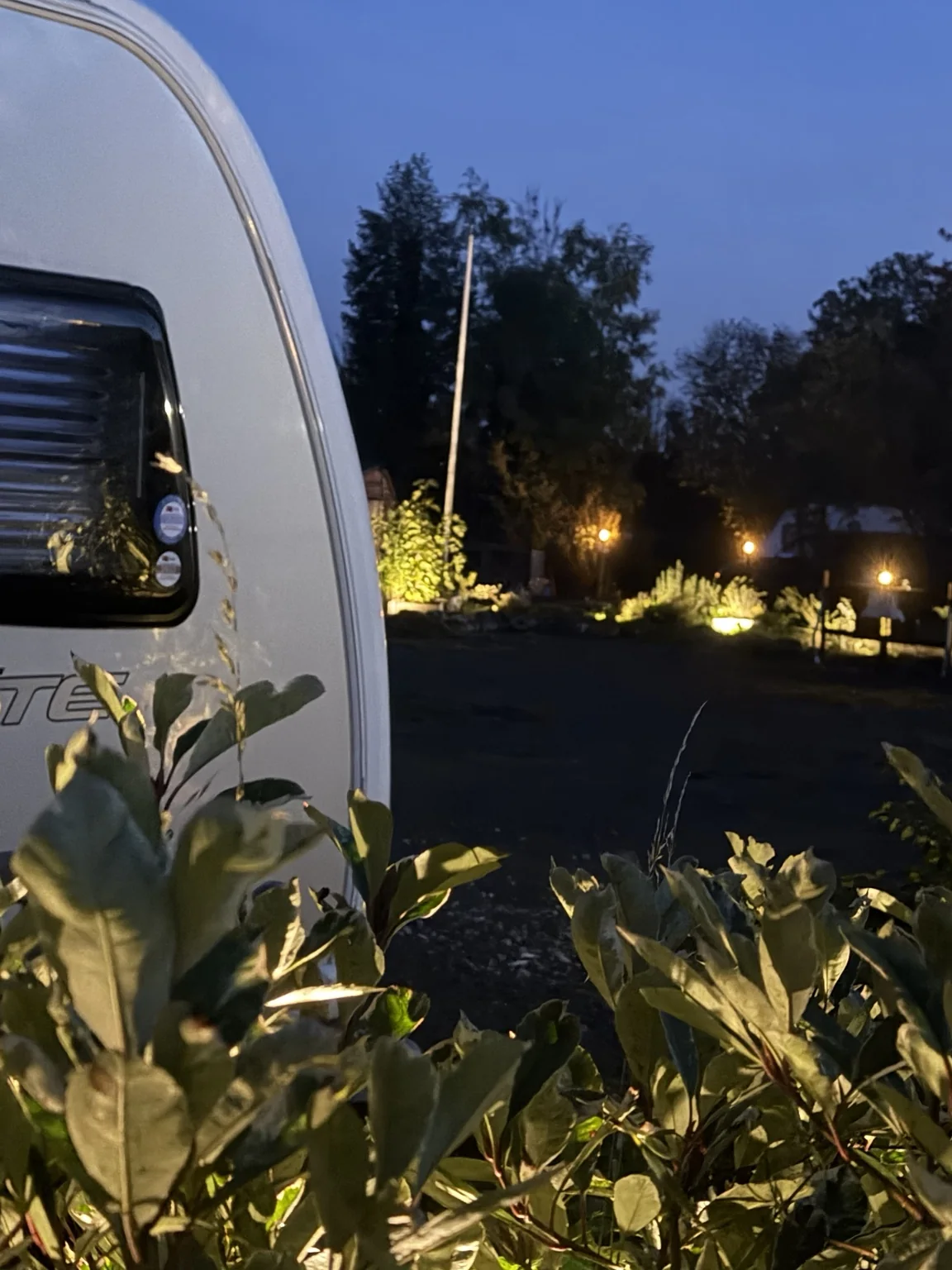 Caravan and softly lit landscaping at Glanfar Meadows during the evening